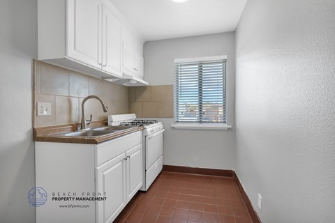 a kitchen with white cabinets and a window